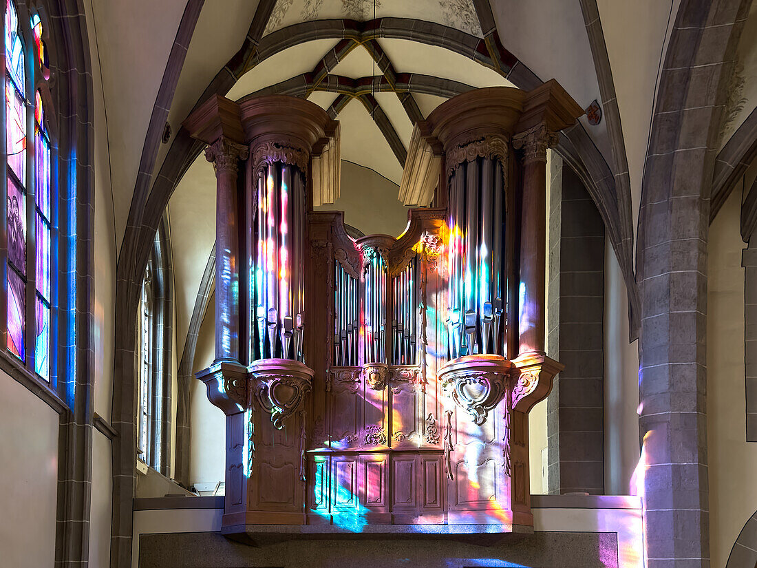 Organ prospectus of a historic portal organ in the sun shining through a colorful church window, St. Johann Baptist, Bad Honnef, North Rhine-Westphalia, Germany