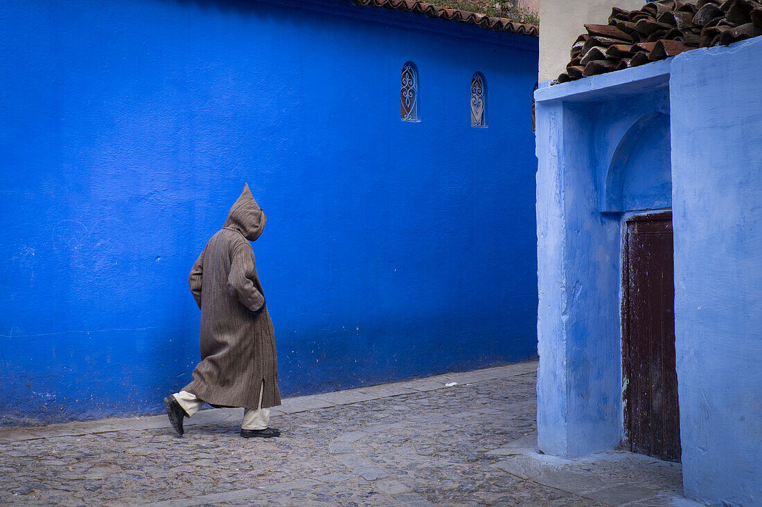 Marokko. Ein Mann geht durch eine Gasse in der blau getünchten Stadt Chefchaouen.
