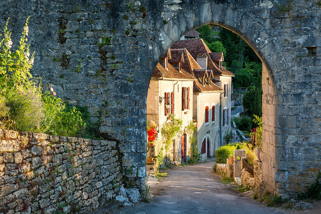 Setting sunlight on homes at entry gate to Saint-Cirq-Lapopie, Lot Valley, Midi-Pyrenees, France