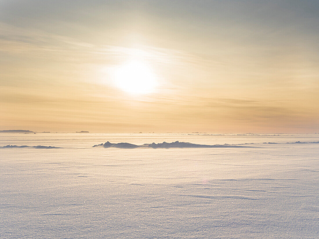 Sonnenuntergang über der stürmischen und gefrorenen Bucht von Melville, in der Nähe von Kullorsuaq im äußersten Norden von Westgrönland.