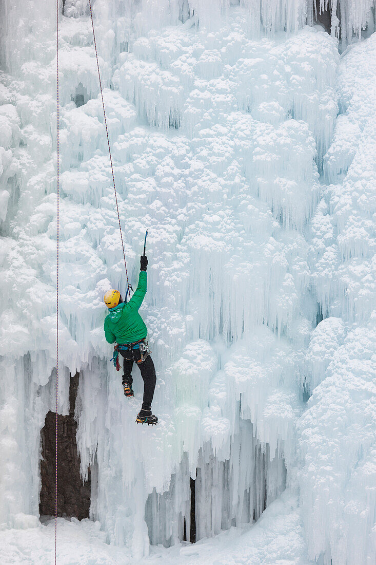 USA, Colorado, Uncompahgre National Forest. Climber ascends ice-encrusted cliff face