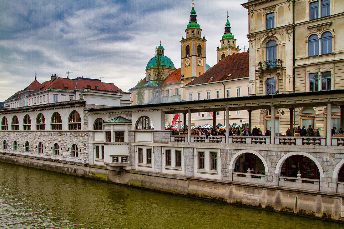 Gebäude und Markthalle am Fluss unter bewölktem Himmel, Ljubljana, Hauptstadt von Slowenien, Europa