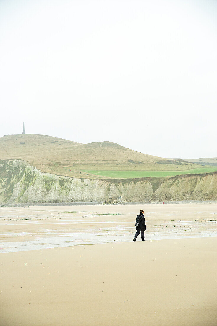 Woman walking on beach of Cap Blanc-Nez, Escalles, France.