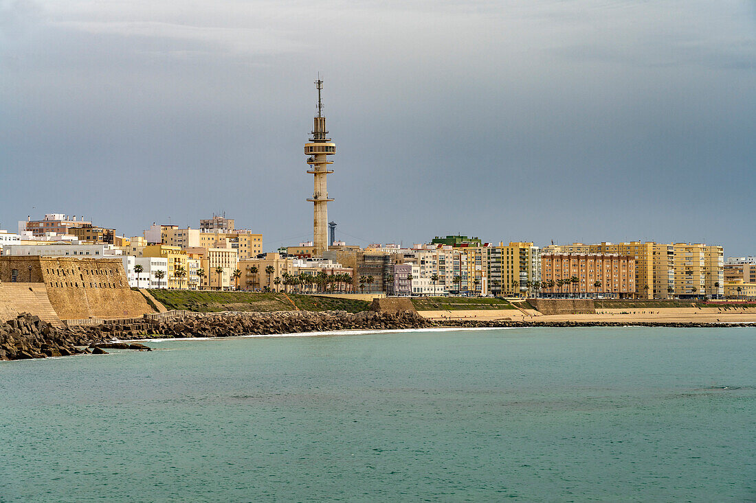 Die Küste mit dem Telekommunikations Turm La Torre Tavira II und dem Strand Playa de Santa María del Mar in Cádiz, Andalusien, Spanien 