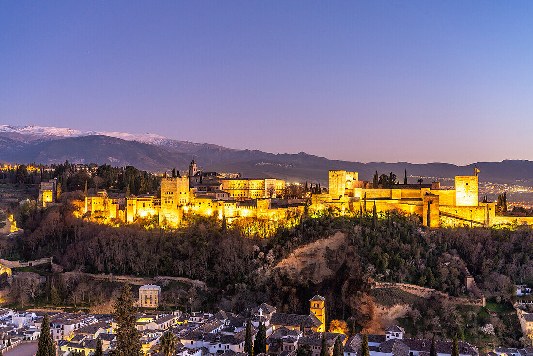 Blick vom Mirador de San Nicolas auf Alhambra und die schneebedeckten Berge der Sierra Nevada in der Abenddämmerung, Granada, Andalusien, Spanien