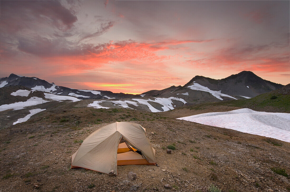 Ein kleines Zelt, das bei Sonnenuntergang in der Wildnis des Mount Baker auf einem Schirmhang direkt unterhalb der Schneegrenze aufgeschlagen wurde.