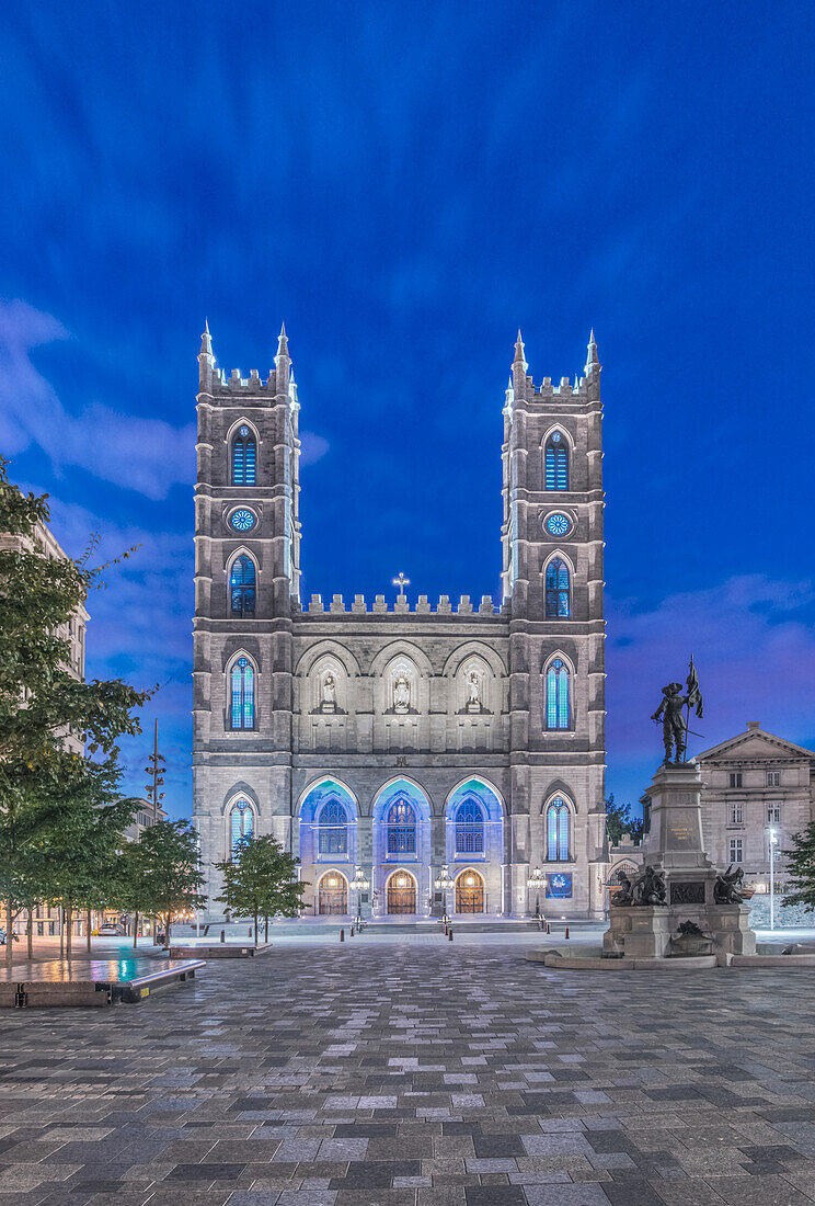 Die Notre-Dame-Basilika, beleuchtet in der Abenddämmerung auf dem Stadtplatz in der Altstadt von Montreal.