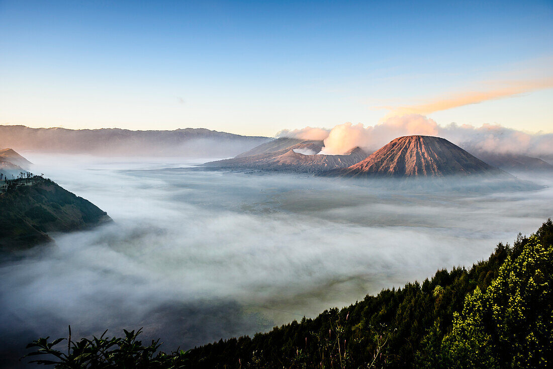 Mount Bromo volcano, a somma volcano and part of the Tengger mountains range, the cone rising above mist in the landscape.
