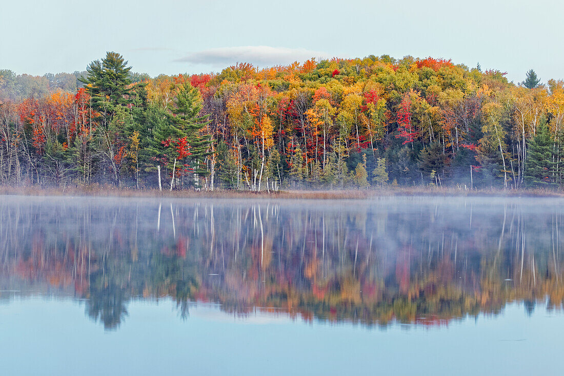Herbstfarben und Nebel reflektieren Council Lake bei Sonnenaufgang, Hiawatha National Forest, obere Halbinsel von Michigan.