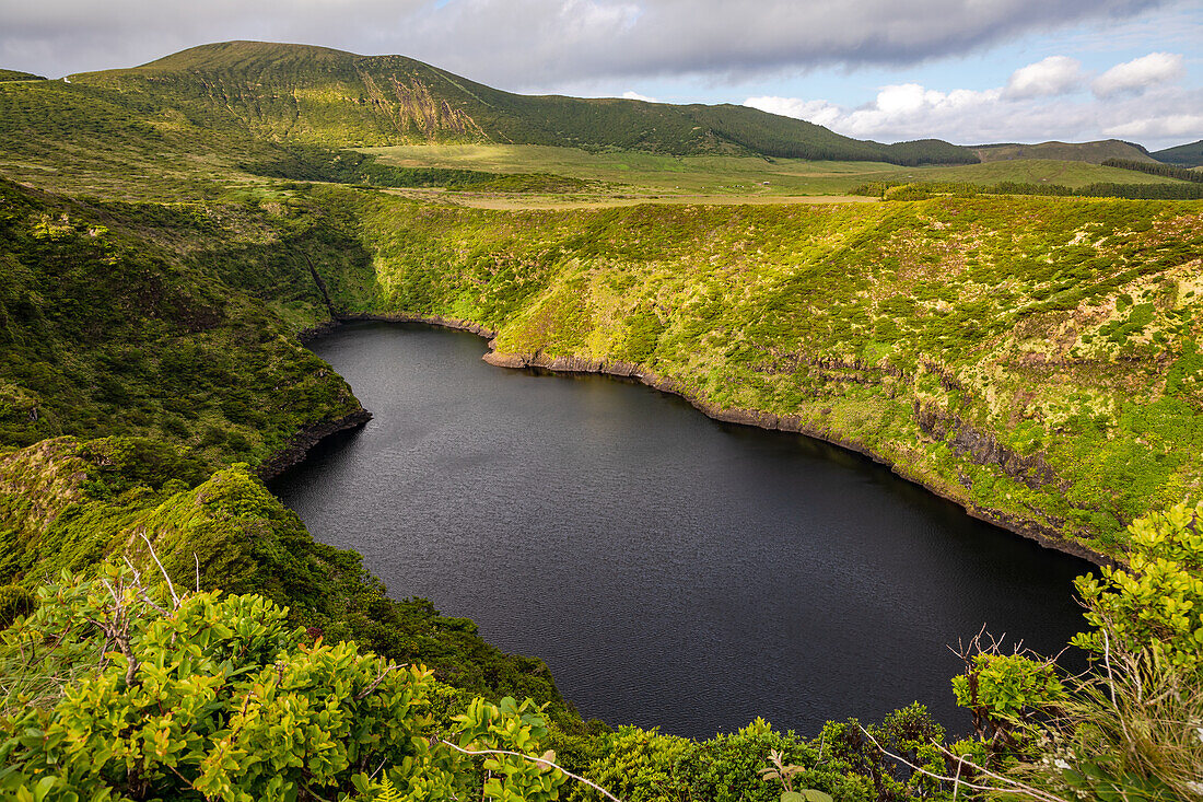 Die schwarze Lagune Lagoa Negra in satt bewachsener Landschaft vom Krater der Caldeira Negra, Flores, Azoren, Portugal