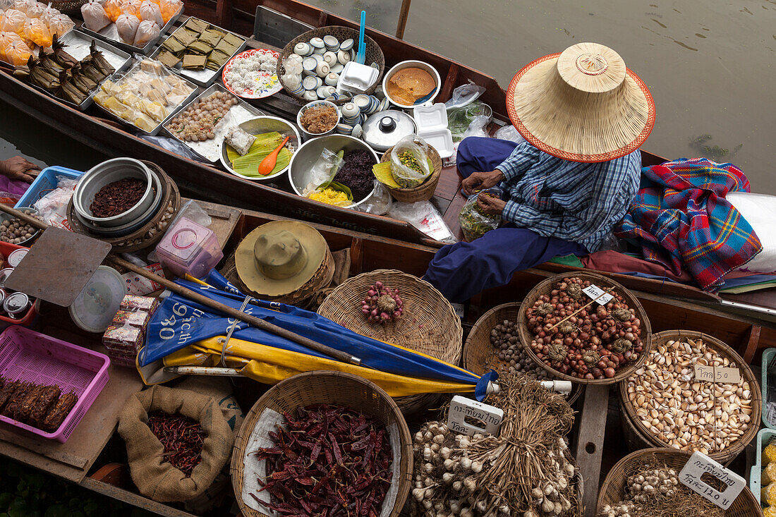 Thailand, schwimmender Markt Amphawa. Frau bereitet in ihrem Einbaum Essen für Kunden zu.