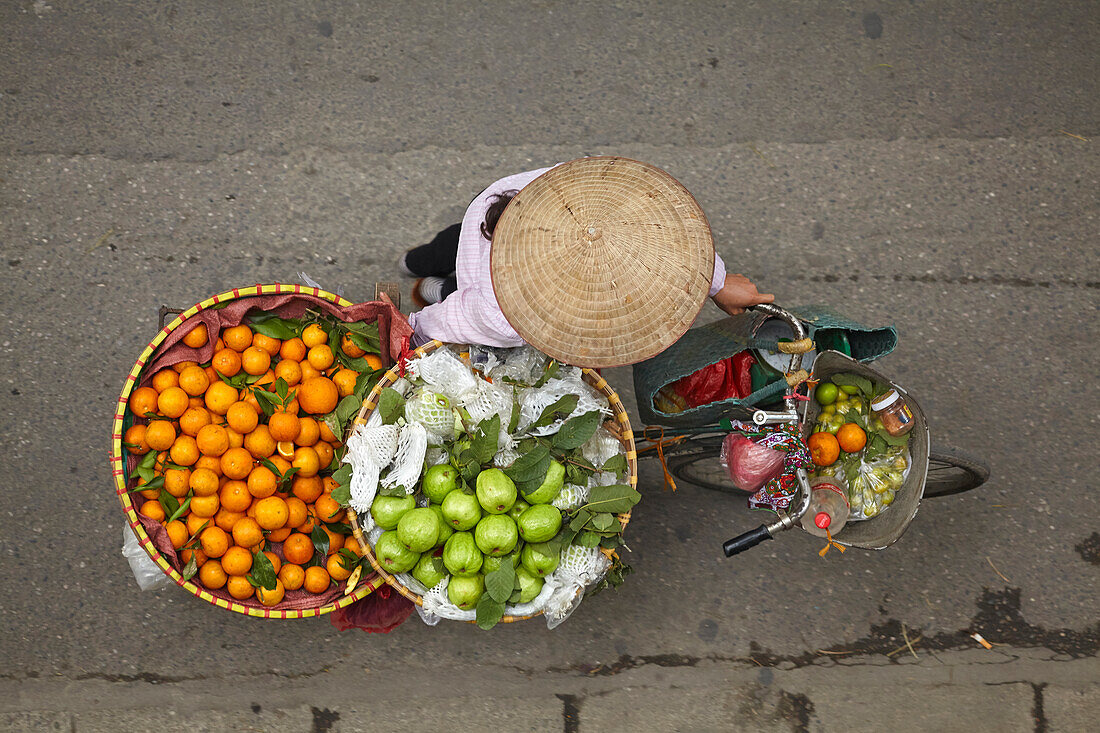Street vendor with round baskets of fruit on bicycle, Old Quarter, Hanoi, Vietnam