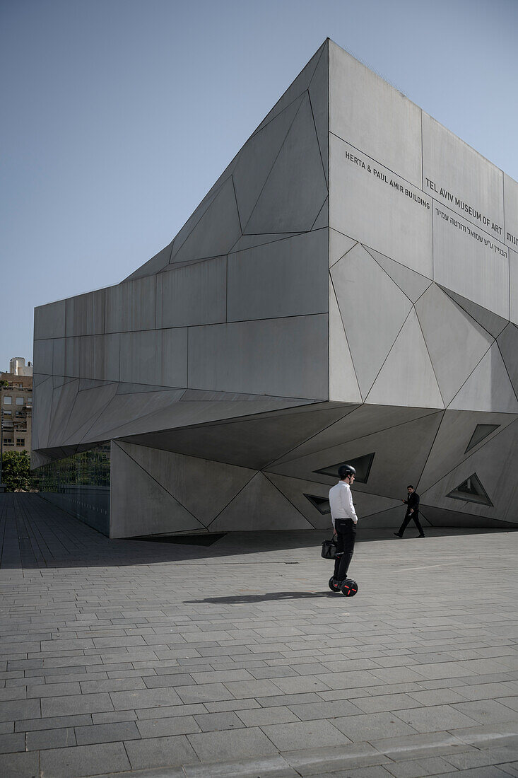 Businessman mit Aktentasche fährt auf Hoverboard am Tel Aviv Kunstmuseum vorbei, Israel, Mittlerer Osten, Asien