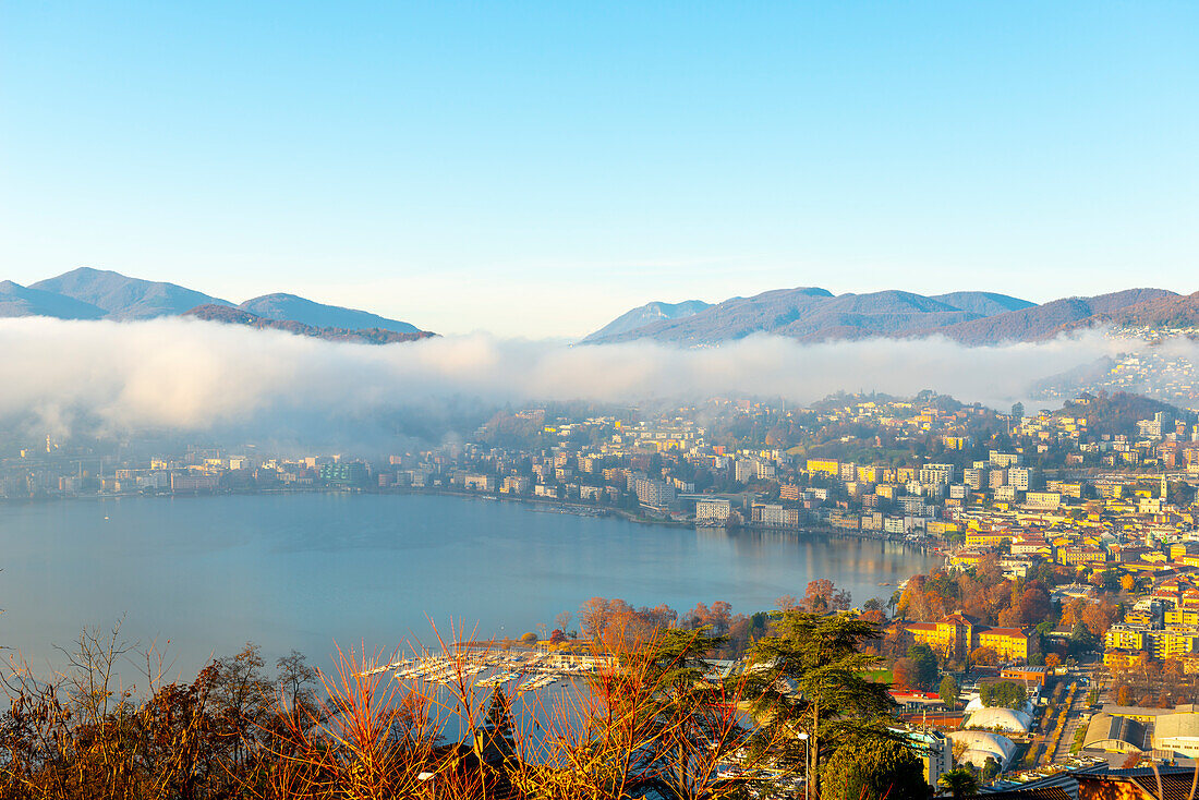 Mountain Range Above Cloudscape and Lake Lugano with Sunlight and Clear Sky in City of Lugano, Ticino in Switzerland.