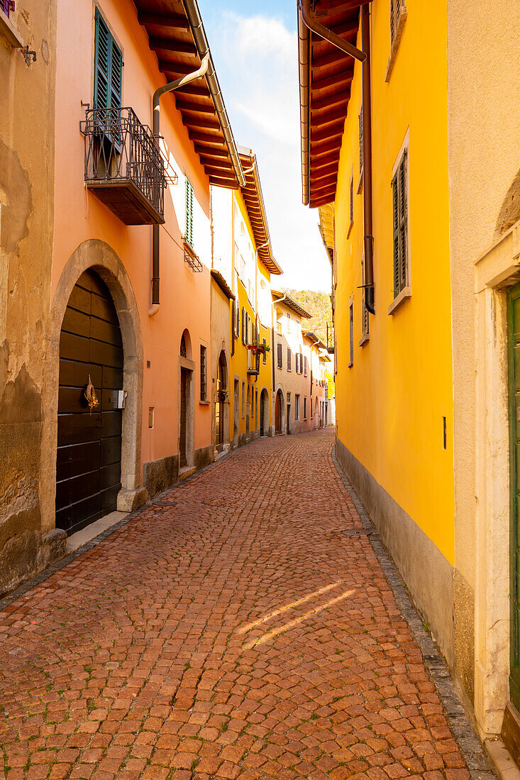 Gasse mit alten Häusern an einem sonnigen Tag in Arzo, Tessin, Schweiz.