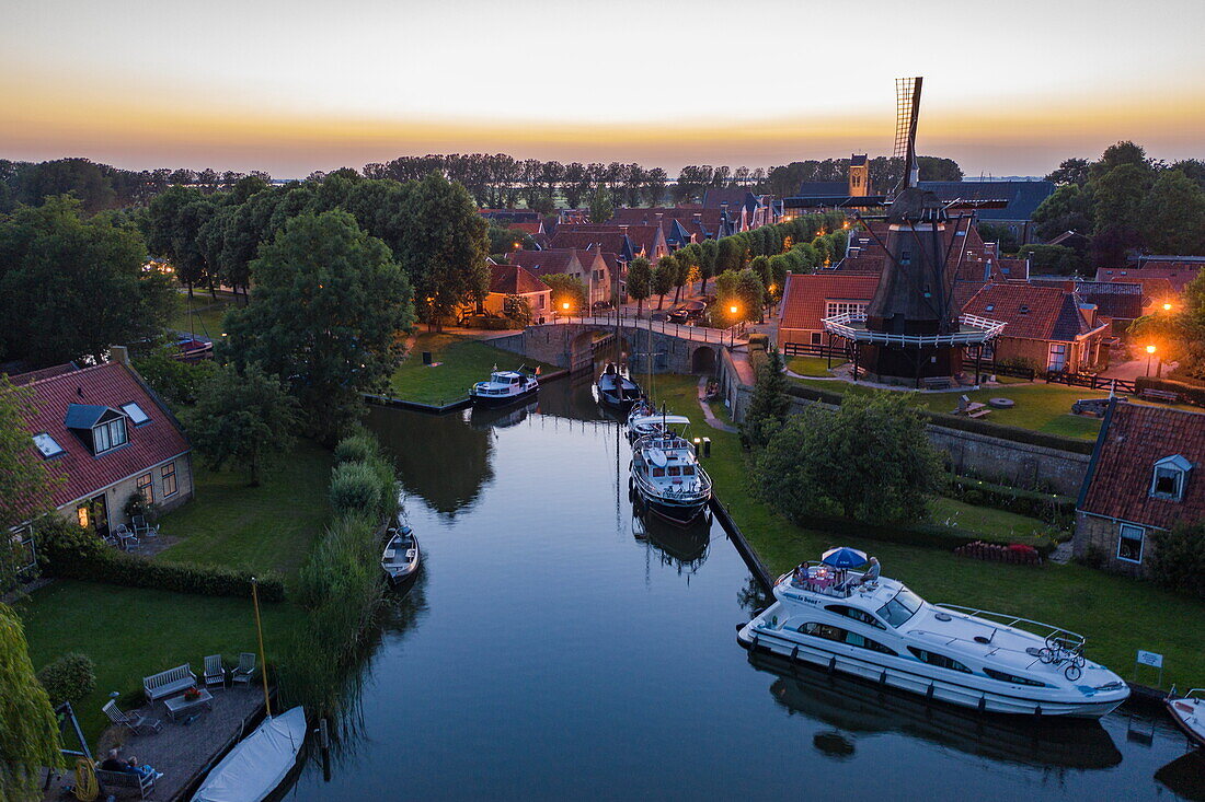 Luftaufnahme von Le Boat Elegance Hausboot am Stadtanleger vor Windmühle De Kaai in der Abenddämmerung, Sloten, Friesland, Niederlande, Europa