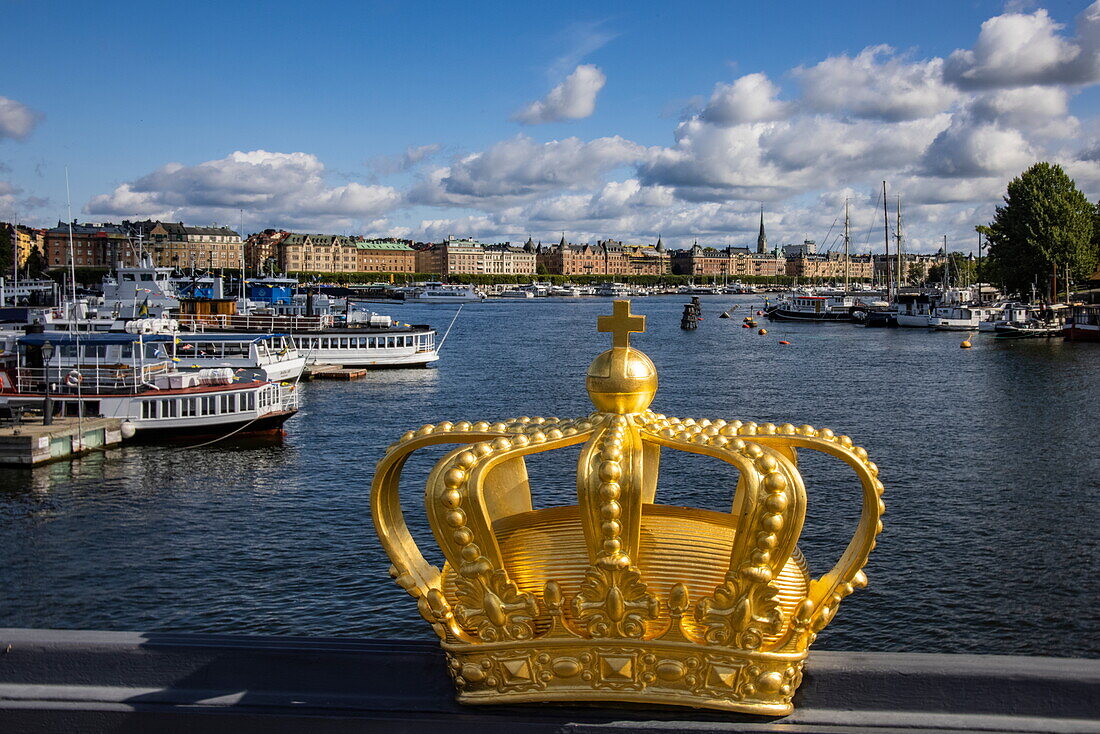 Goldene Krone auf Skeppsholmen Brücke mit Booten im Hafen dahinter, Stockholm, Schweden, Europa