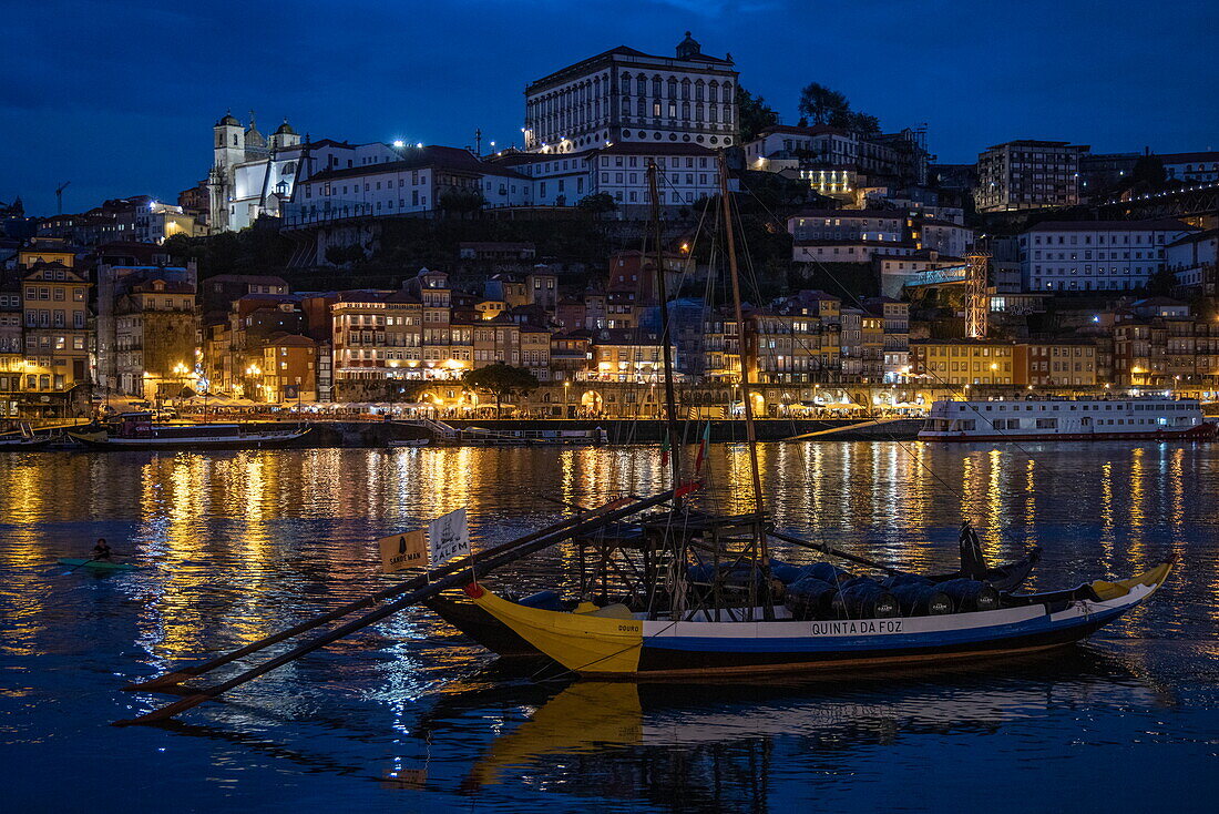 Traditional port wine transport boat on the Douro river overlooking Ribeira old town and historic center at dusk, Vila Nova de Gaia, Porto, Portugal, Europe