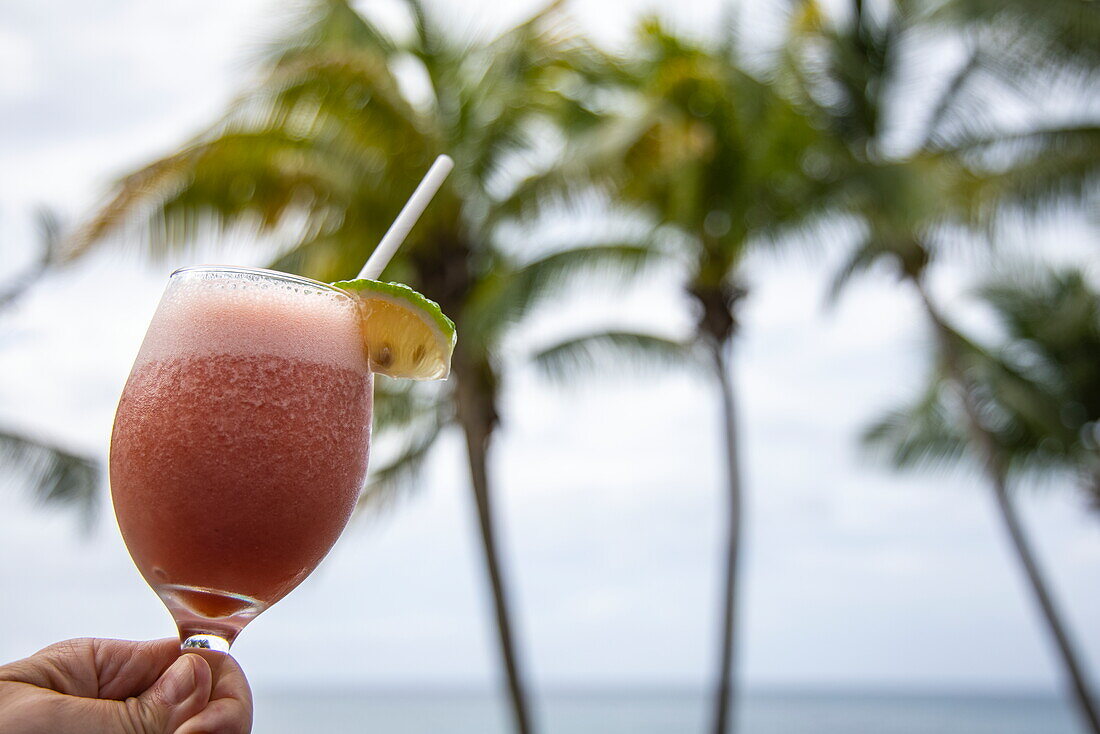 Close up of fruit punch at Laluna Resort with coconut trees behind, Morne Rouge, Saint George, Grenada, Caribbean