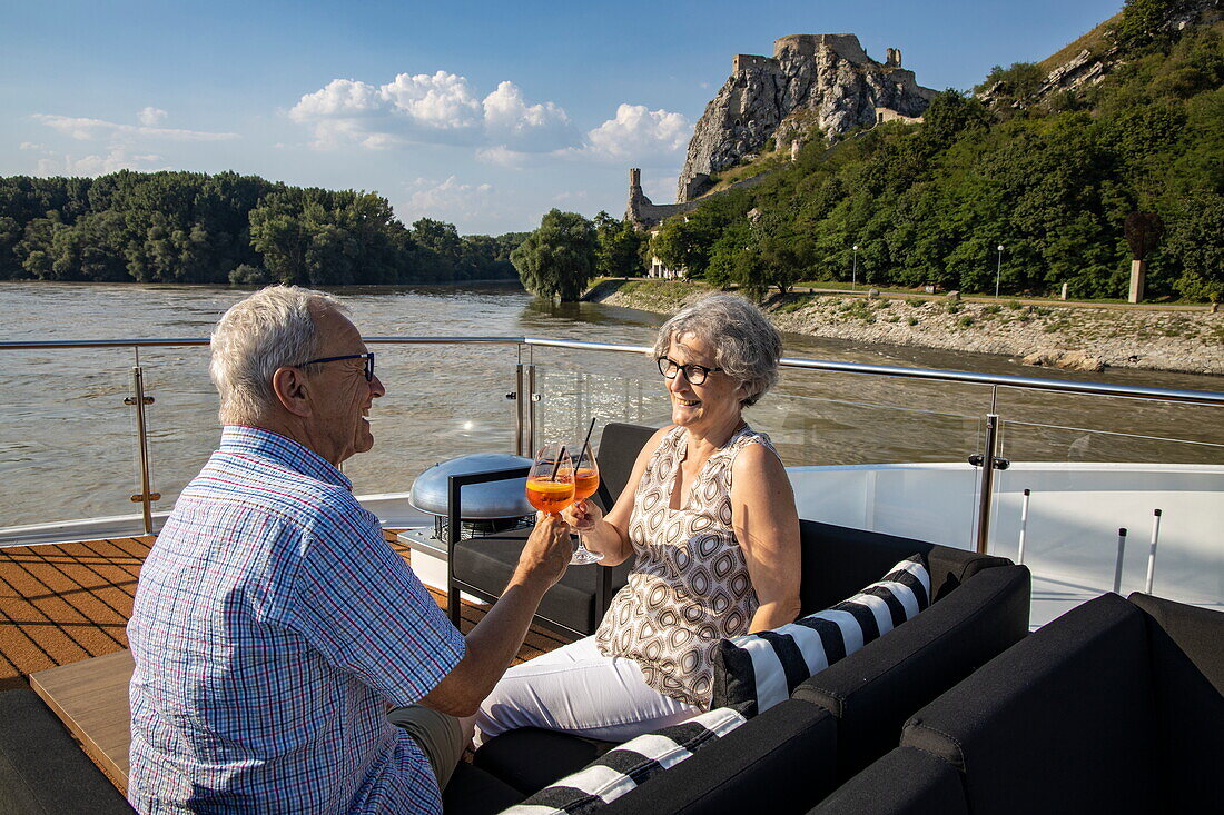 Paar genießt Aperol Spritz Cocktails auf dem Sonnendeck von Flusskreuzfahrtschiff Excellence Empress auf der Donau, in der Nähe von Hainburg a.d. Donau, Niederösterreich, Österreich, Europa