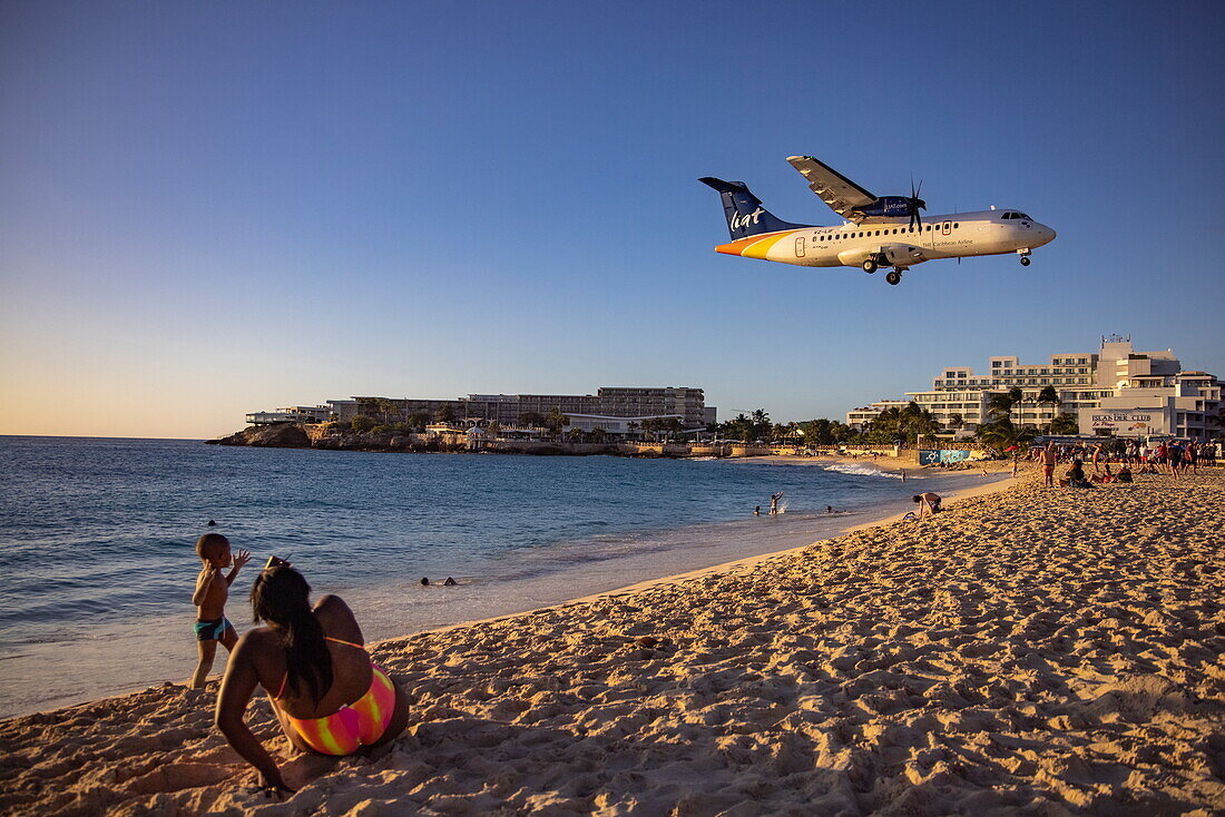 People on Maho Beach admire the landing of a Liat Airline ATR 42-600 aircraft at Princess Juliana International Airport, Saint Martin (Sint Maarten), Caribbean