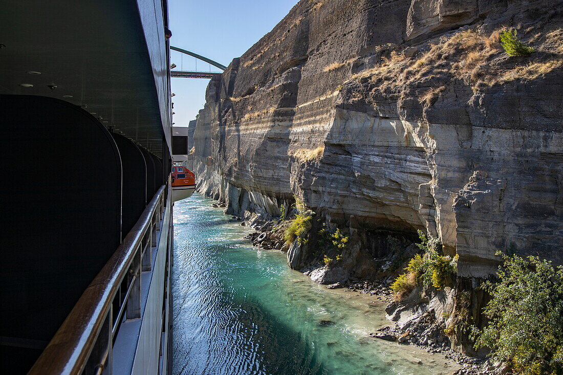Side of expedition cruise ship World Explorer (Nicko Cruises) behind a tugboat during passage of the Corinth Canal, near Corinth, Peloponnese, Greece, Europe
