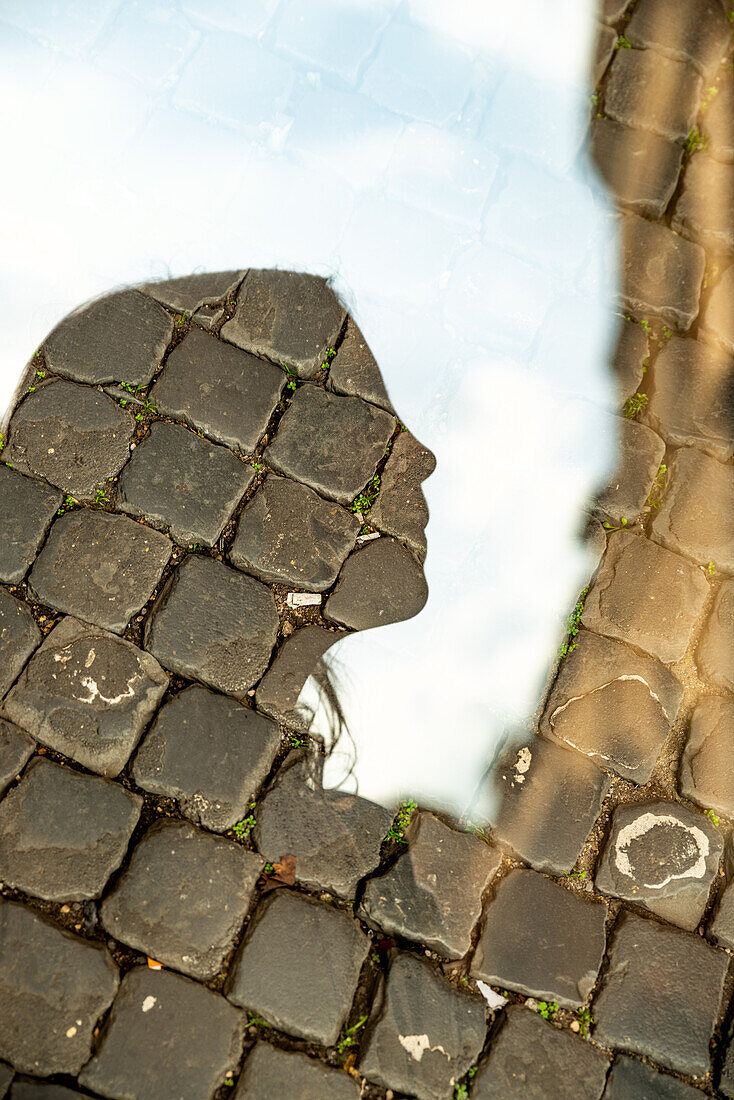 Double exposure portrait of a girl, looking in profile, and a roman cobblestone street.