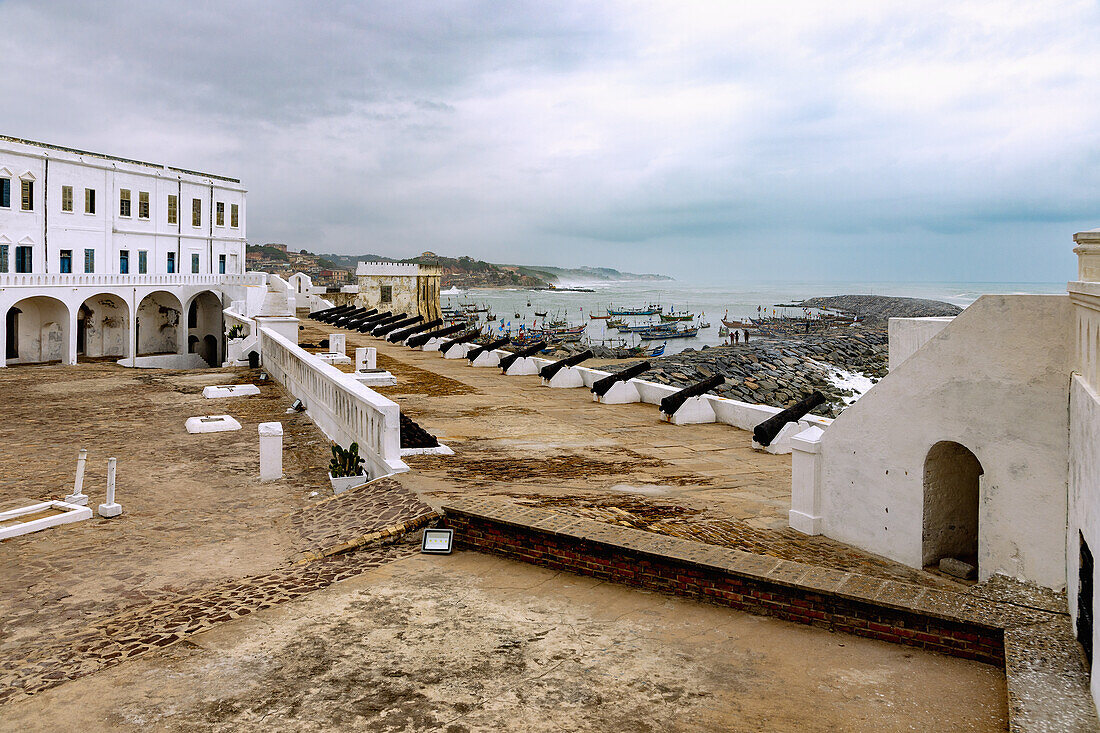 Cape Coast Castle und Blick auf Fischerhafen in Cape Coast an der Goldküste in der Central Region im Süden von Ghana in Westafrika