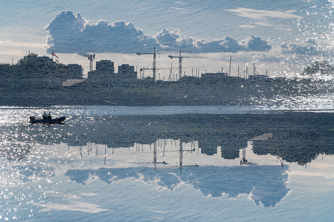 Doppelbelichtung. Baukräne in Kopenhagen mit einem Schlauchboot im Vordergrund