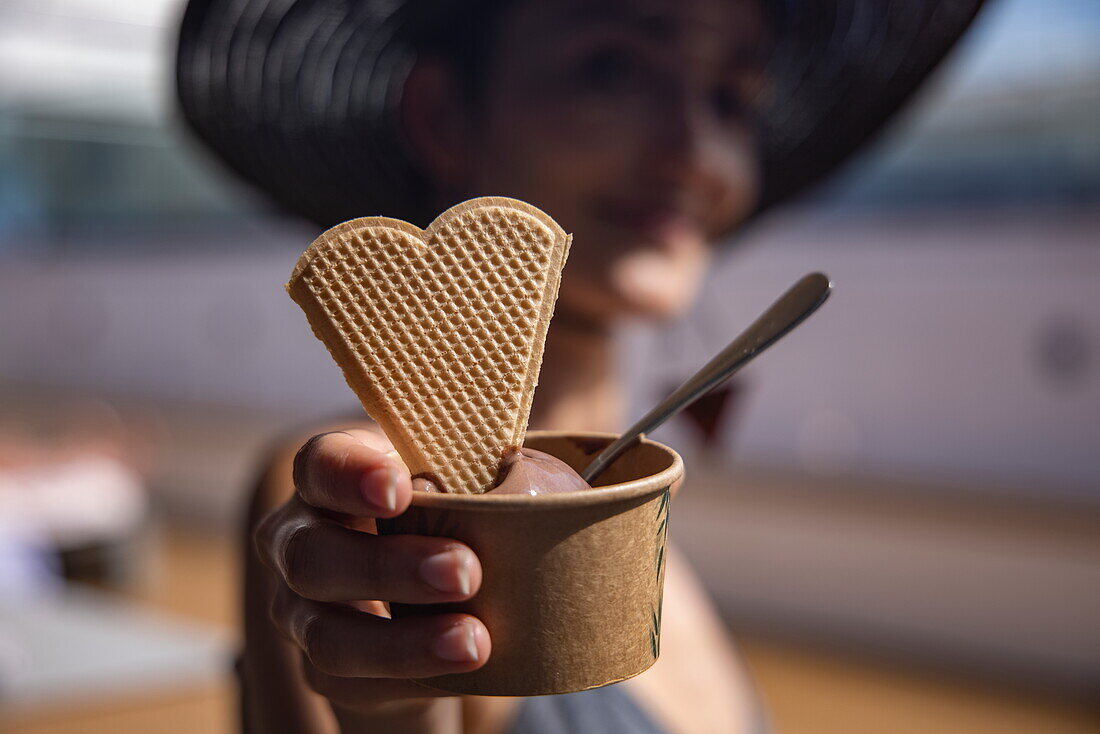Detail of cup of ice cream with heart-shaped waffle in young woman's hands aboard expedition cruise ship World Voyager (Nicko Cruises), Caribbean Sea, near Nicaragua, Central America