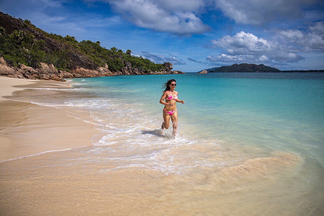 Junge Frau läuft am Strand von Anse St. Jose, Insel Curieuse, Seychellen, Indischer Ozean