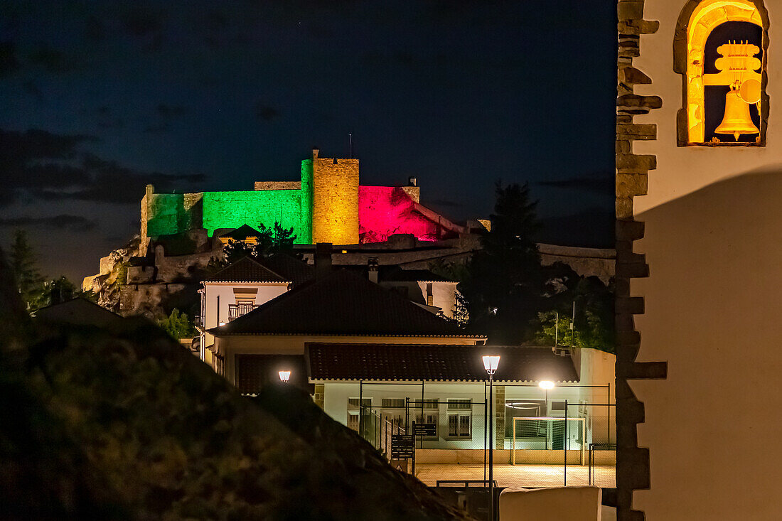 Die Burg und Stadtmauer der Stadt Marvao abends angestrahlt mit den Farben grün und rot der portugiesischen Flagge, Portugal