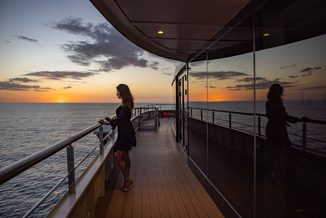 Frau steht an Reling und bewundert den Sonnenuntergang von an Bord Expeditionskreuzfahrtschiff World Voyager (nicko cruises), Pazifischer Ozean, in der Nähe von Panama, Mittelamerika