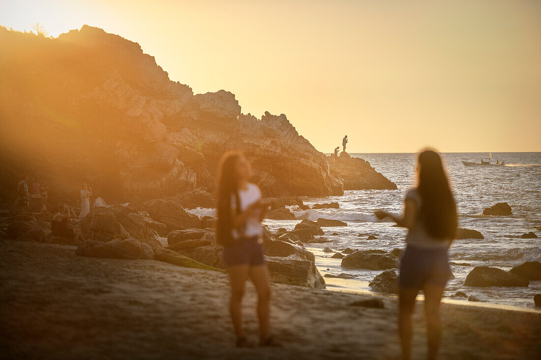 Mädchen genießen den Sonnenuntergang am Surf Spot Playa Zicatela, Puerto Escondido, Oaxaca, Mexiko, Pazifischer Ozean, Lateinamerika, Nordamerika, Amerika