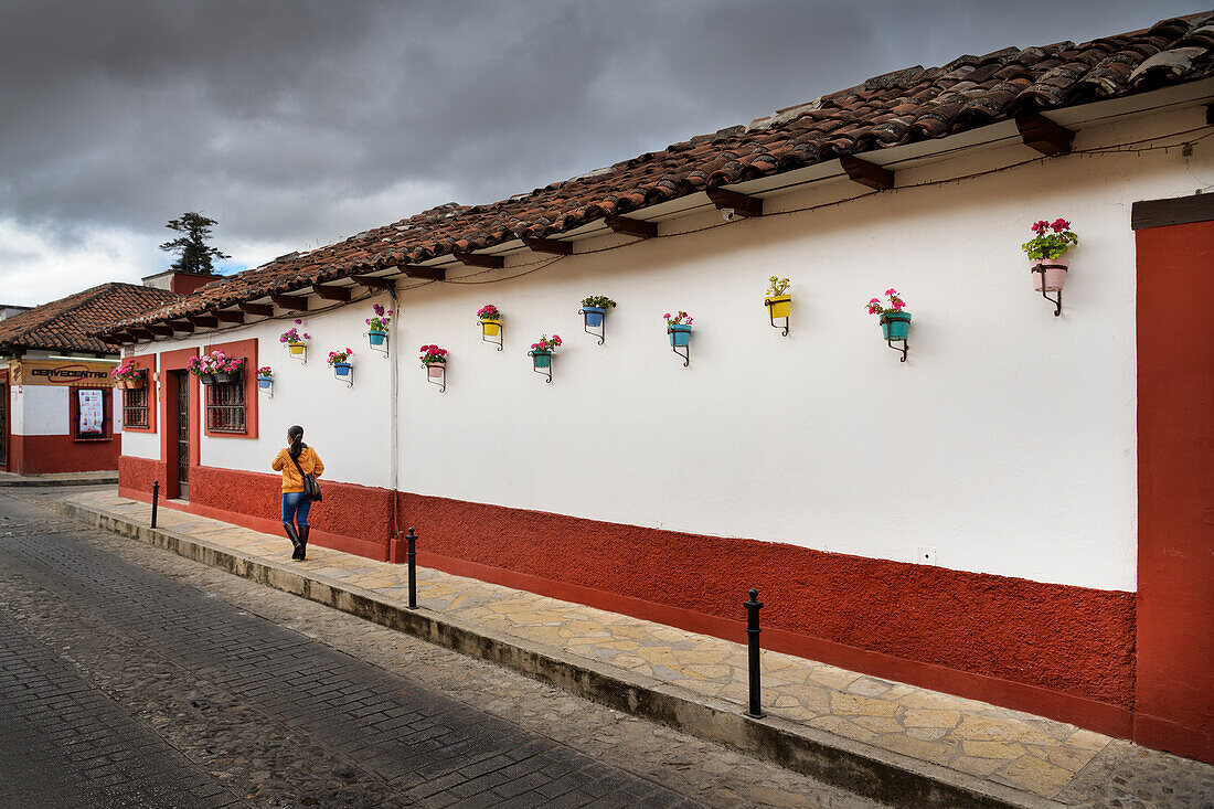 Frau läuft an einer geschmückten Häuserfassade entlang, San Cristóbal de las Casas, zentrales Hochland (Sierra Madre de Chiapas), Mexiko, Nordamerika, Amerika