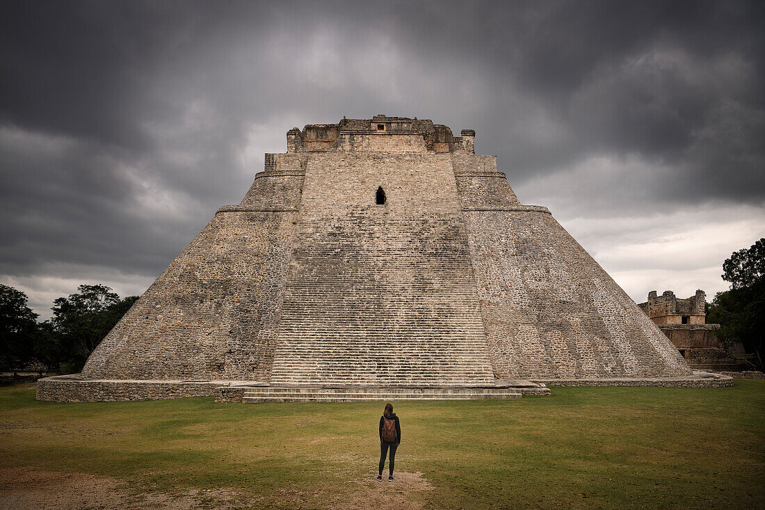 Frau steht vor Pyramide des Zauberers (Pirámide del Adivino), Archäologische Zone Uxmal, Maya Ruinenstadt, Yucatán, Mexiko, Zentralamerika, Nordamerika, Amerika