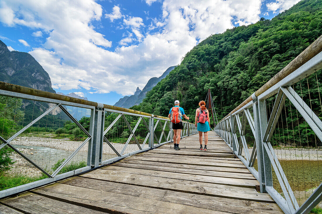 Mann und Frau wandern auf Brücke über den Fluss Cordevole, Belluneser Höhenweg, Dolomiten, Venezien, Venetien, Italien