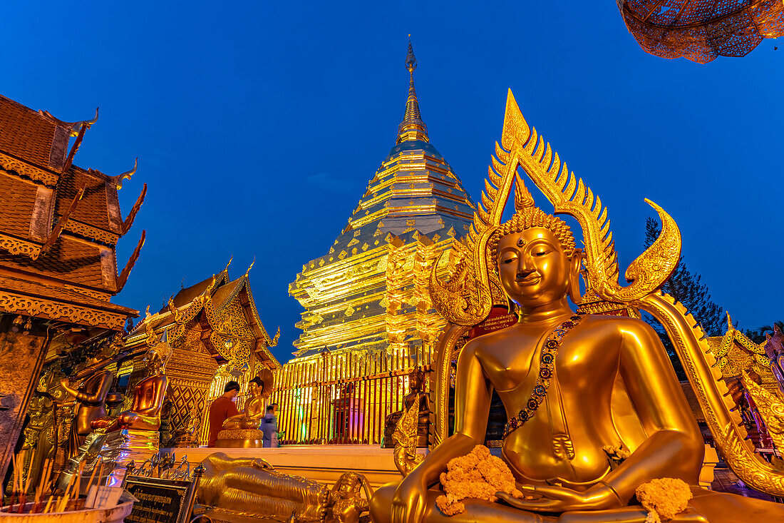 Buddha Statue und Goldener Chedi der buddhistischen Tempelanlage Wat Phra That Doi Suthep, Wahrzeichen von Chiang Mai in der Abenddämmerung, Thailand, Asien  