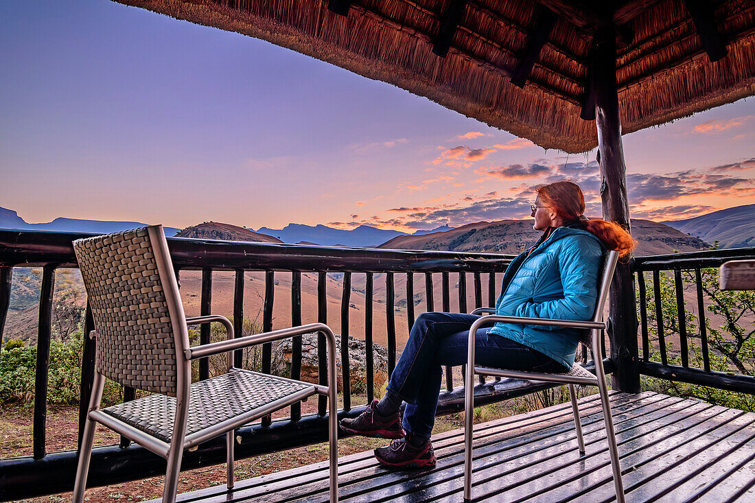 Frau sitzt auf der Terrasse der Giant's Castle Lodge und blickt auf Drakensberge, Giant's Castle, Drakensberge, Kwa Zulu Natal, UNESCO Welterbe Maloti-Drakensberg, Südafrika