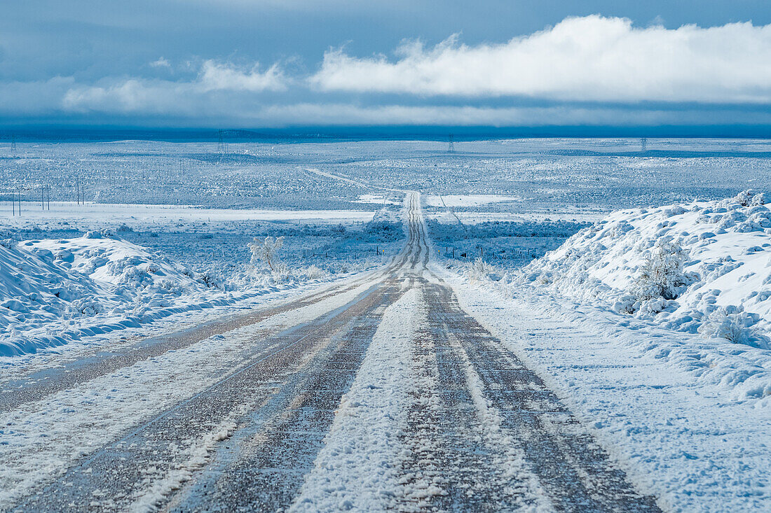 Vereiste Straße, die durch eine verschneite Wüstenlandschaft in Utah führt.