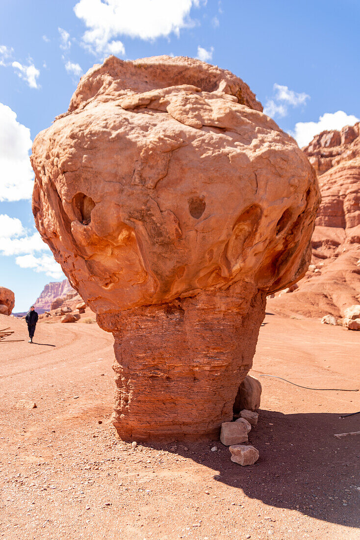 Girl standing behind a eroded sandstone rock in the Arizona desert landscape.