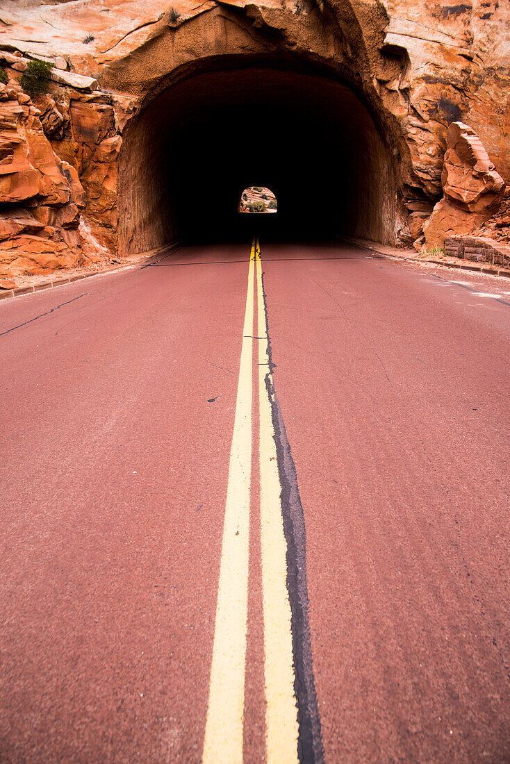 A road leading into a tunnel in the landscape of the Zion National Park in Utah, USA.
