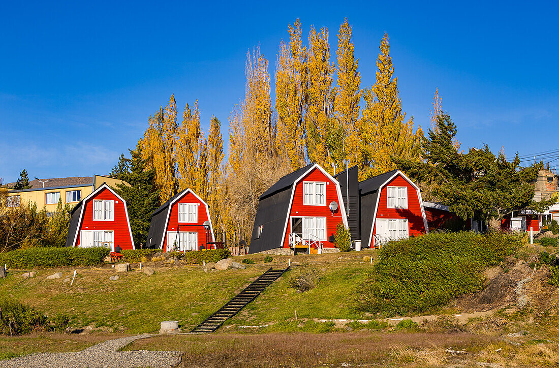 Malerische rote Häuser im Stadtbild von El Calafate mit herbstlichen Bäumen und Farben bei Sonne, Argentinien, Patagonien