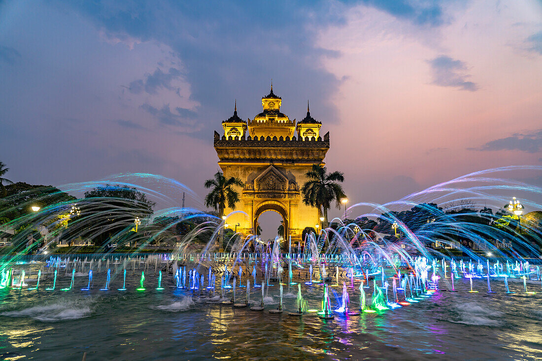 Bunt beleuchteter Brunnen am Siegestor Patuxai in der Abenddämmerung, Hauptstadt Vientiane, Laos, Asien