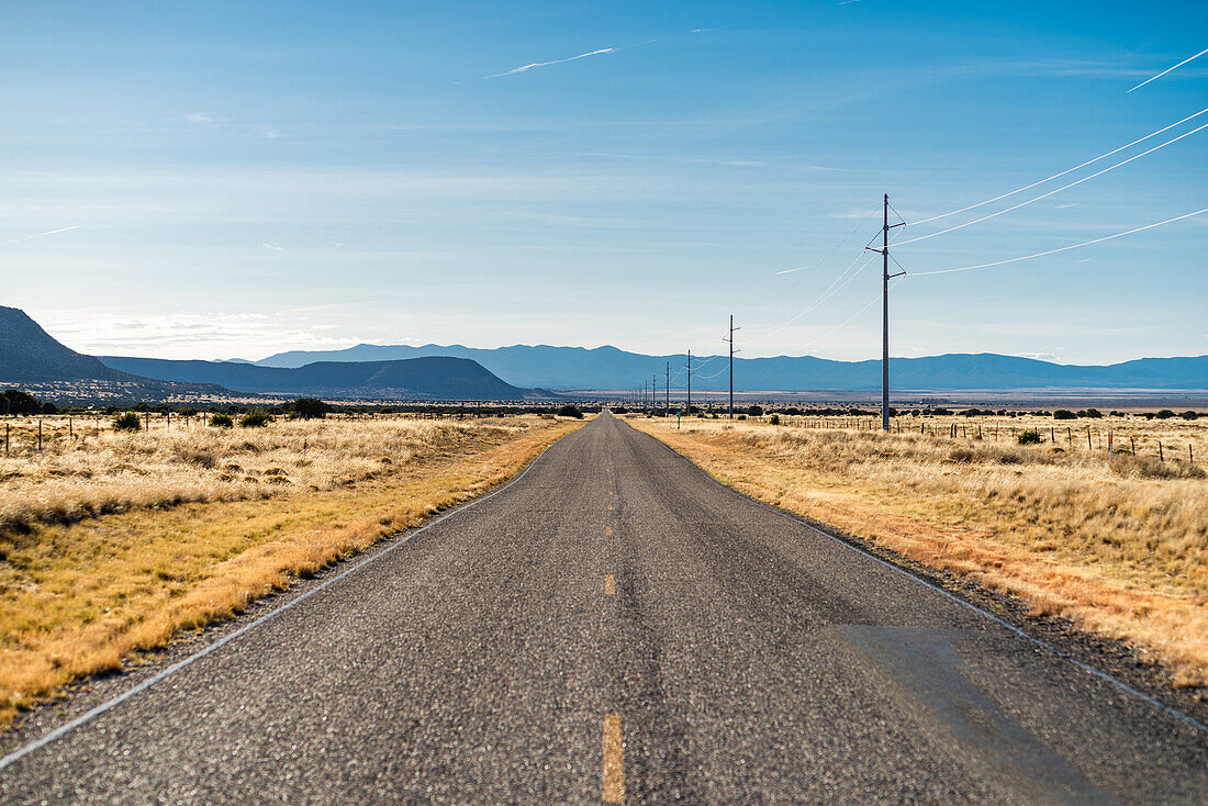 Straße, die sich in eine Prärielandschaft erstreckt, New Mexico, USA