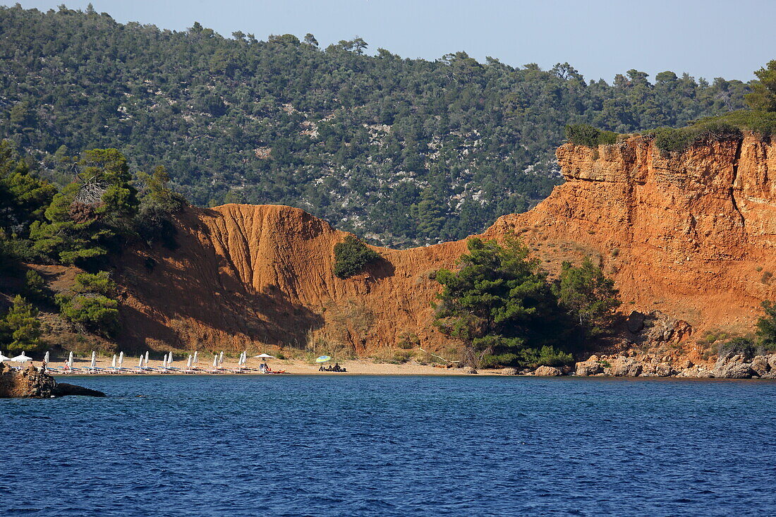 Red rocks line Kokkinokastro beach, Alonissos island, Northern Sporades, Greece