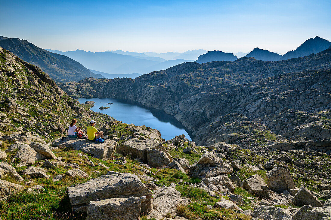 Mann und Frau beim Wandern genießen Blick auf Bergsee, am Refugi Josep Maria Blanc, Nationalpark Aigüestortes i Estany de Sant Maurici, Katalonien, Pyrenäen, Spanien