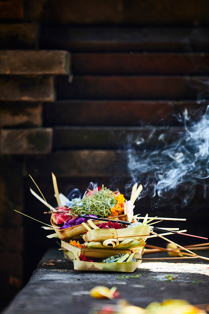 Offerings made of palm leaves with flowers and incense on the steps of a Hindu temple in Gianyar, Bali Indonesia