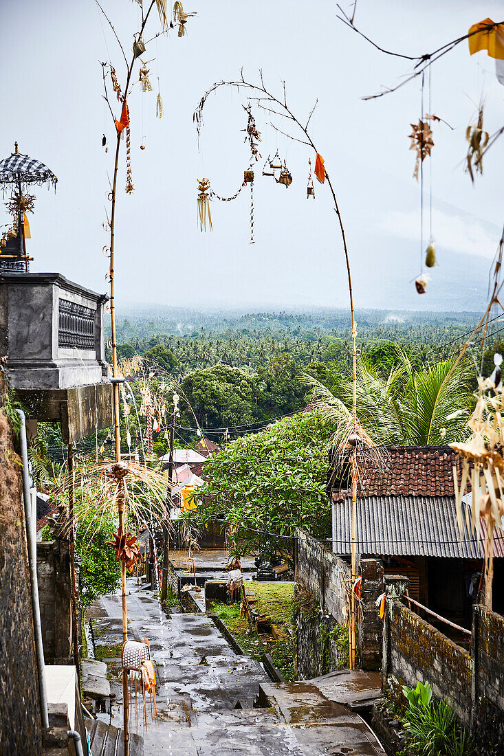 Streets after rain lined with penjor decorations to celebrate Galungan and Kuningan in a traditional village in the Karangasem Regency of Bali, Indonesia.
