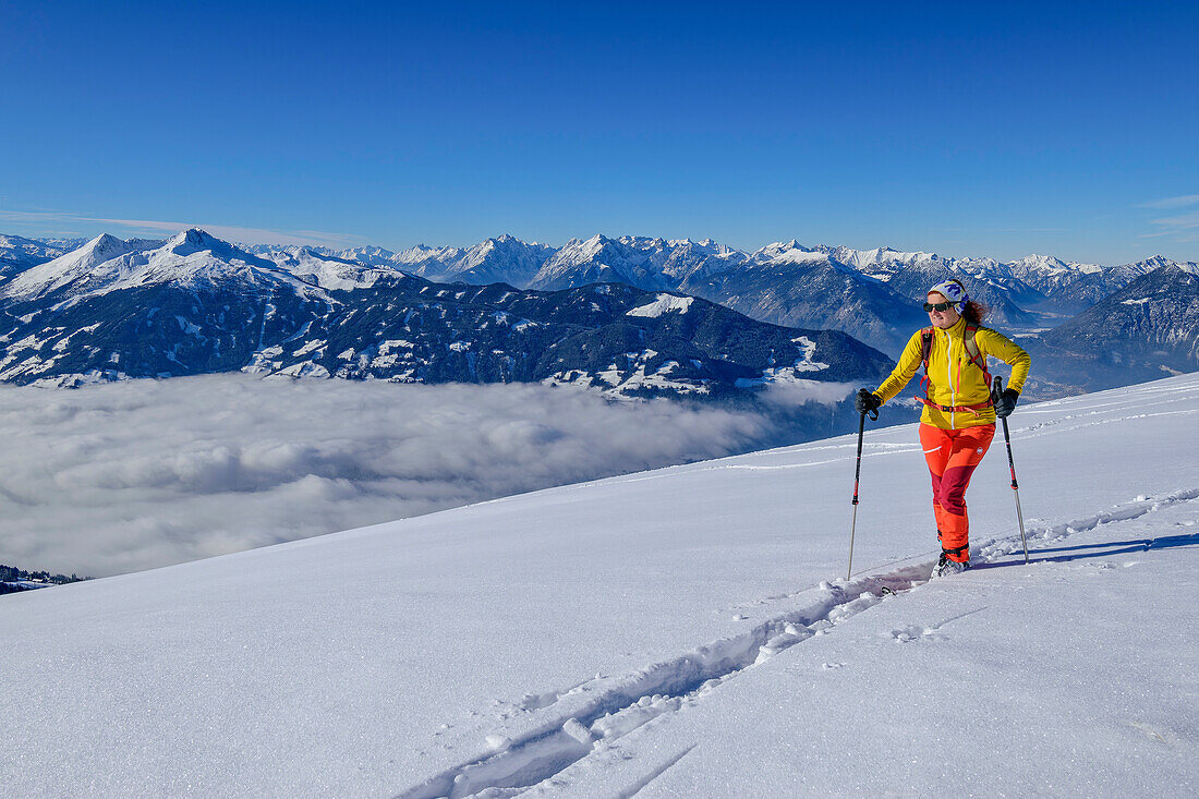 Woman on ski tour ascending to the Standkopf, Kellerjoch and Karwendel in the background, Standkopf, Kitzbühel Alps, Tyrol, Austria
